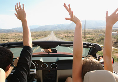 Couple Driving With Hands Raised