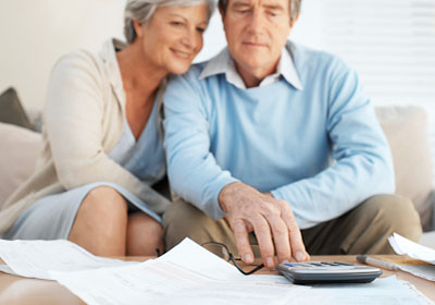 Senior couple calculating finances in living room Senior couple calculating finances in living room